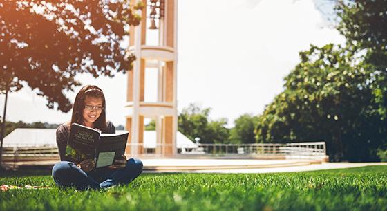 Student reading below the bell tower